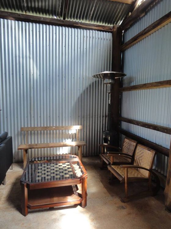 A small nook in the shed with a chess table and bench seating against corrugated iron walls.