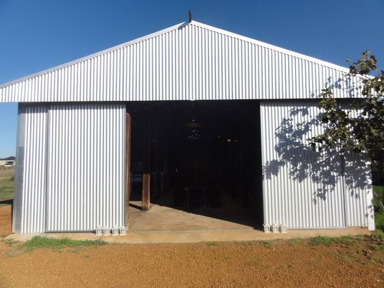 The Old Shed viewed from outside on a clear day, wide sliding doors open onto the concrete apron.