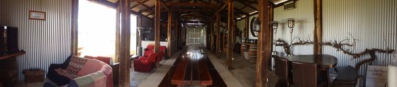 Wide panorama inside the shed showing the timber-post corridor and the long jarrah table.