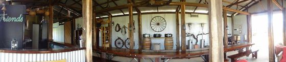 Panoramic view of the bar area inside the shed with a hanging wagon wheel and wine barrels.